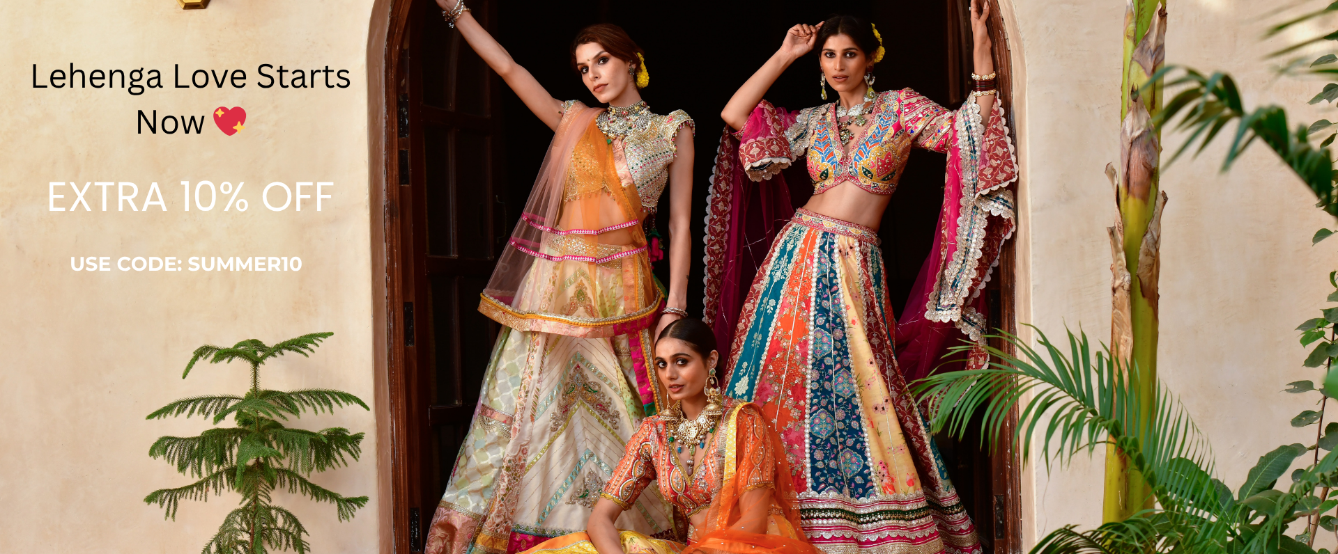 Three women in colorful lehengas standing in a doorway with promotional text overlay.